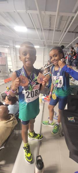 Two Track Express athletes showing their medals at an indoor meet
