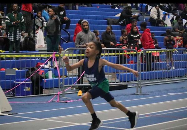 Track Express hurdler clearing a hurdle at an indoor meet